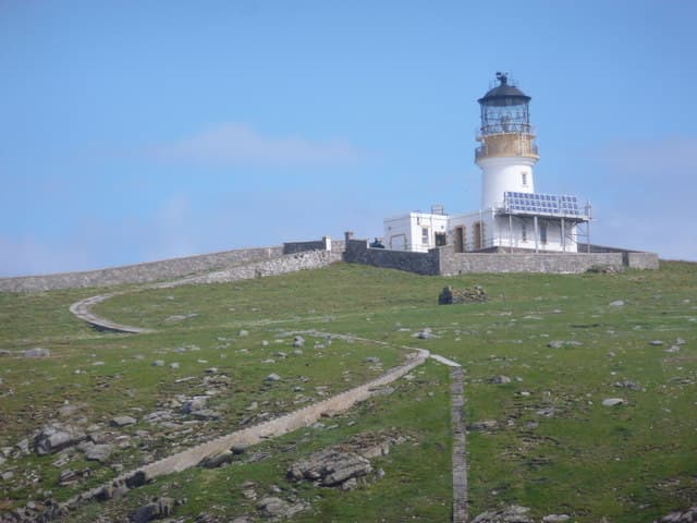 Flannan Isles lighthouse above steep sea cliffs, with the concrete railway housing descending towards the landing.